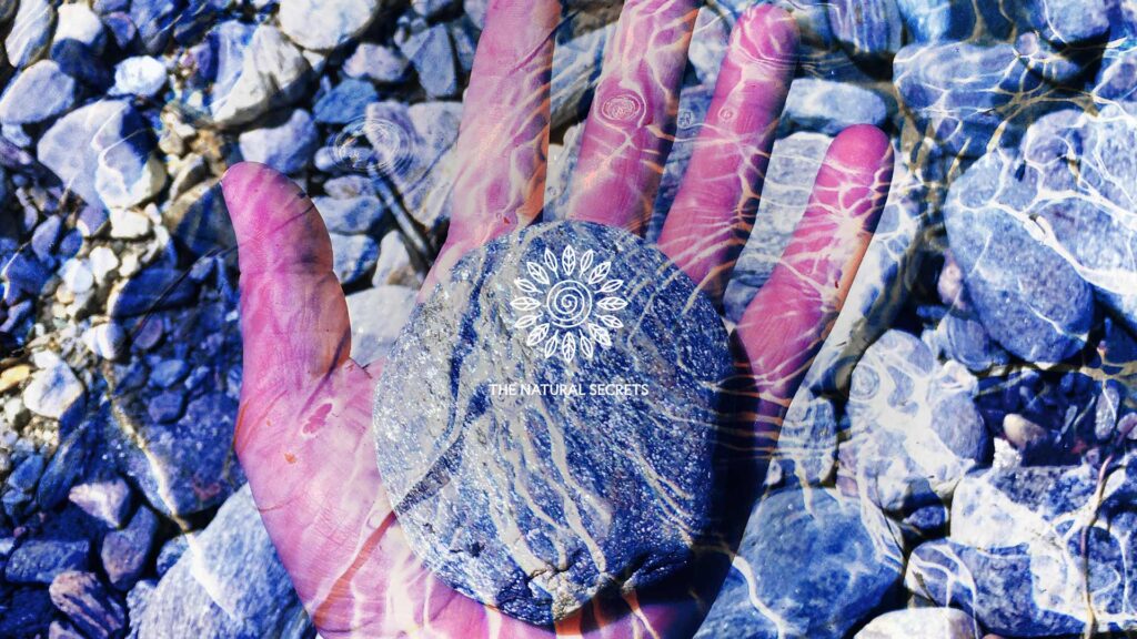 self-awareness begins with interoception, A hand holding a stone, with water reflexions. Image is blue tones.